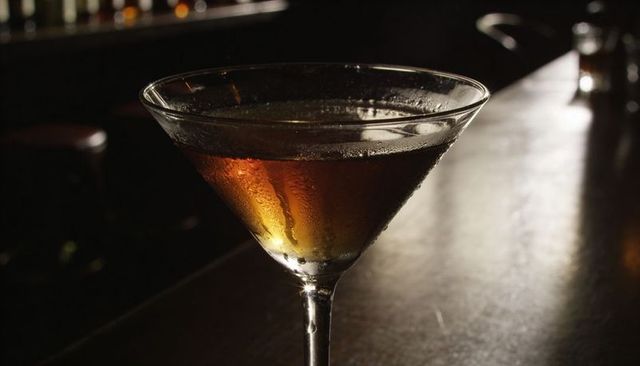 Amber martini in chilled glass on polished bar counter with moody low light