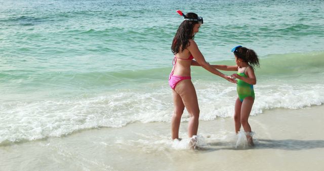 Mother and daughter playing in water at the beach