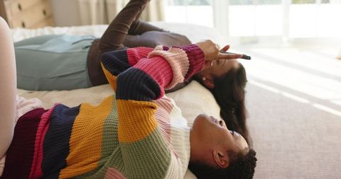 Two Friends Relaxing and Messaging on Bed in Cozy Moment