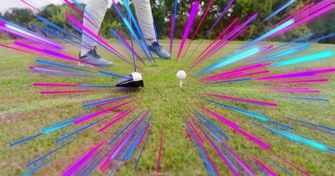 Golfer lining up driver on tee with neon motion streaks ground-level golf action