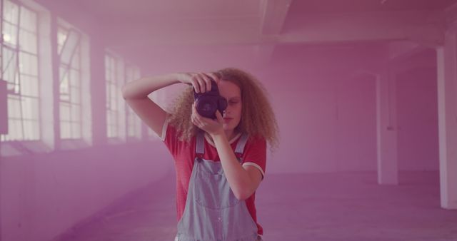 Young photographer with camera in industrial space filled with pink smoke - Download Free Stock Images Pikwizard.com