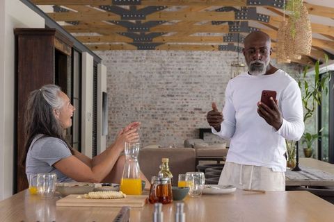 Senior couple having breakfast conversation in sunlit modern kitchen with exposed beams
