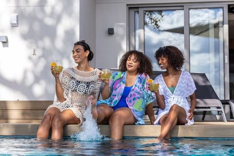 Relaxing poolside with diverse friends sipping cocktails, wearing beach coverups