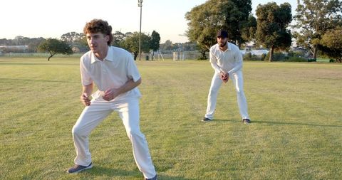 Two Fielders Crouching on Suburban Cricket Ground During Golden Hour Practice