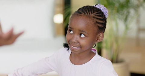 African american girl smiling and looking up while sitting in cozy living room with plant