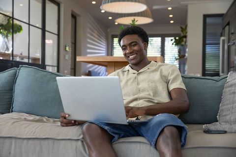 Relaxed Man Using Laptop on Sofa in Modern Living Space