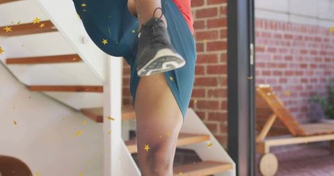 Performing high-knee exercise on stair landing at home with sneaker and confetti