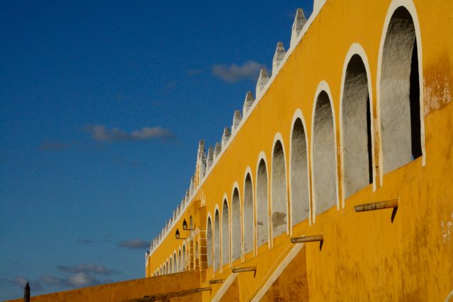 This photo captures a historic colonial building with bright yellow walls and white arched windows under a clear blue sky. Ideal for use in travel brochures, historical blog posts, or architectural design presentations to showcase cultural heritage and vibrant tourism destinations.