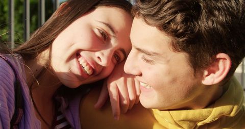 Happy teenage couple relaxing outdoors in sunlight