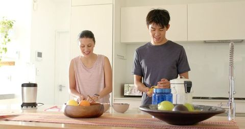 Couple preparing fresh citrus together in bright modern kitchen for healthy breakfast