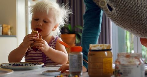 Blonde Child Eating Pancakes With Sibling at Home