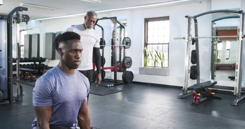 Personal Trainer Coaching Client on Kneeling Lunge Technique in Modern Gym