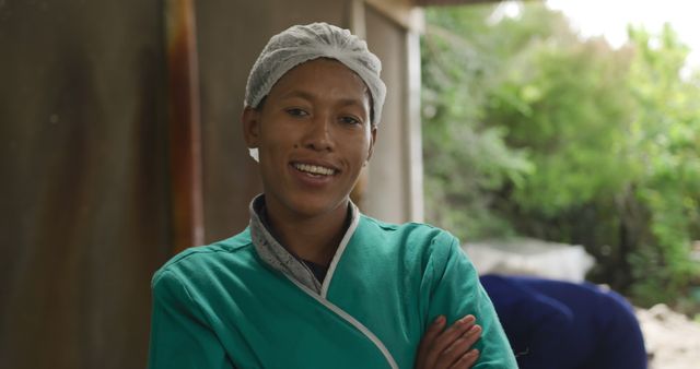 Smiling nurse in a green scrub stands confidently outdoors. Her warm expression conveys compassion and professionalism in healthcare.