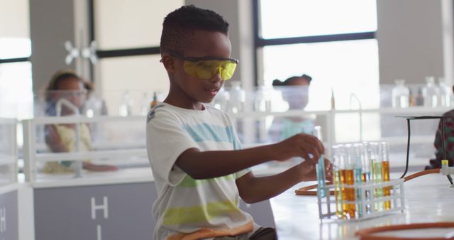 Image of happy african american boy wearing glasses during chemistry lesson. primary school education and learning concept.