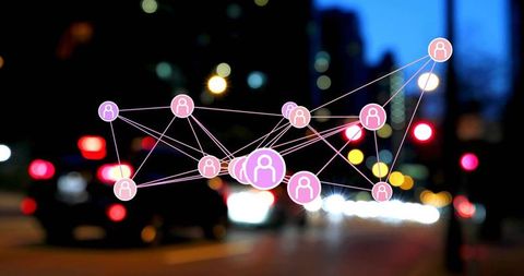 Digital social network overlay in urban nightscape connecting user icons with bokeh lights