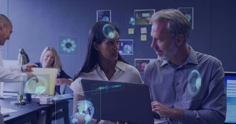 Business team collaborating with holographic data while analyzing laptop in tech office