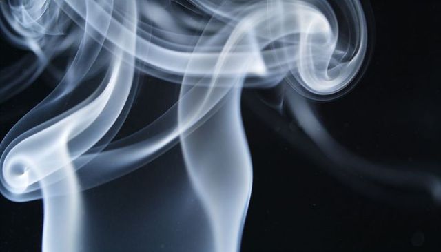 Luminous smoke ribbons forming ethereal spirals against deep black backdrop