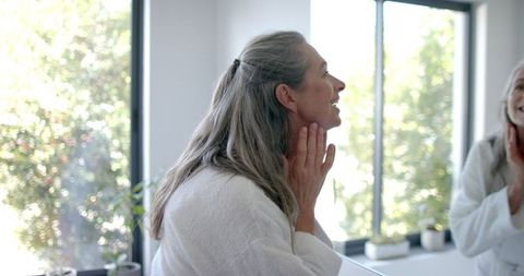 Mature woman examing her reflection by window