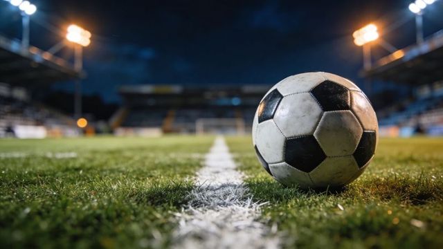Close-up soccer ball resting on center line under stadium floodlights at night, shallow depth