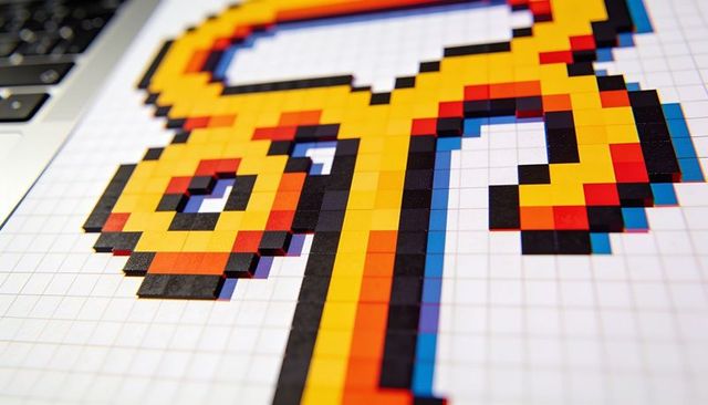 Creating colorful pixel-art mosaic on graph paper using tile stickers with laptop keyboard