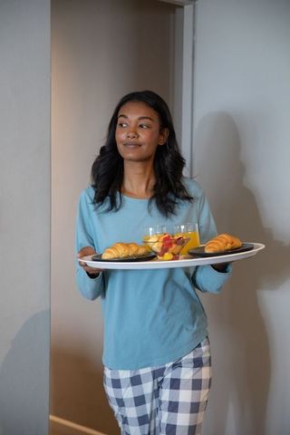 Confident Woman Carrying Breakfast Tray with Croissants and Juice