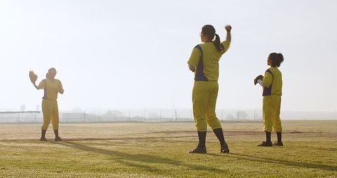 Female softball team practicing on grass field