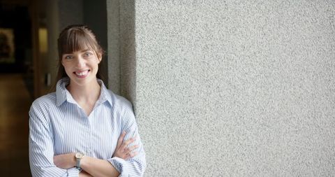 Confident Smiling Woman Standing with Arms Crossed in Casual Office