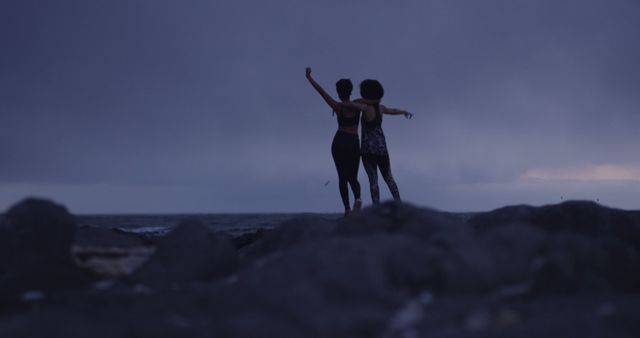 Two Friends Embracing on Rocky Beach at Dusk - Download Free Stock Images Pikwizard.com