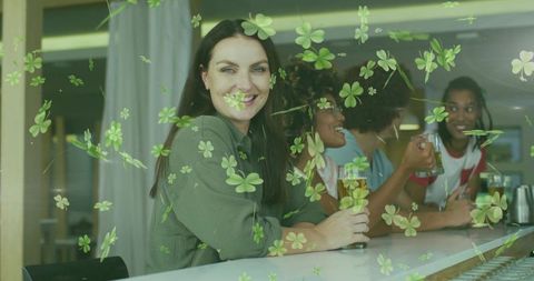 Smiling woman holding pint at bar with clover overlay, friends enjoying drinks
