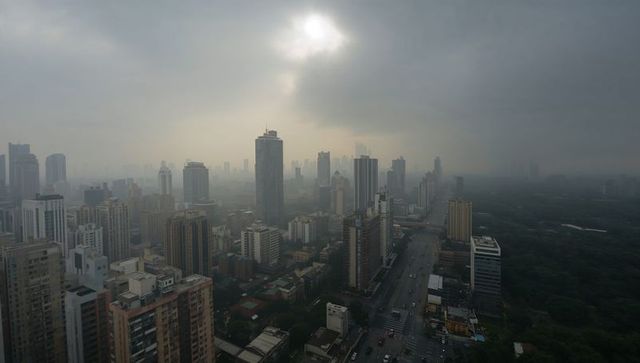 Modern skyline emerging through morning haze with urban park
