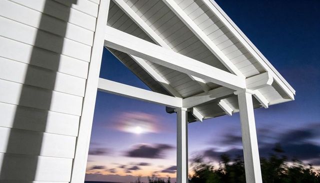 White porch gable with exposed rafters framing coastal twilight moon halo and shadowplay
