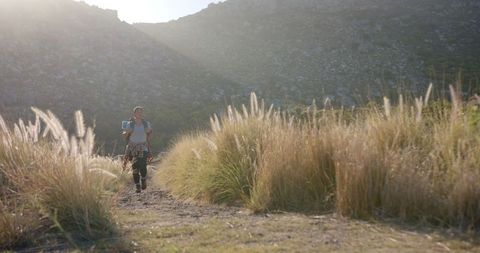 Woman hiking trail in sunlit mountain landscape