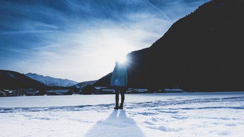 Lone figure in snowy valley with mountain silhouette