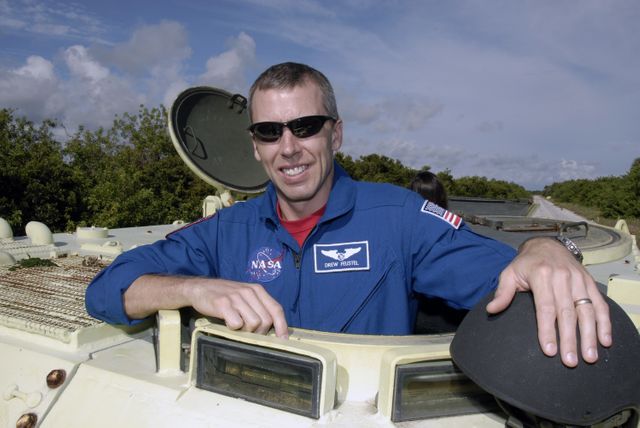Astronaut in a blue NASA suit preparing to drive an M-113 armored personnel carrier. Useful for educational articles about astronaut training, space missions, emergency procedures, and NASA operations. Highlighting Kennedy Space Center activities and space mission preparations.
