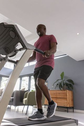 Active Senior Man Running on Treadmill at Home with Modern Decor