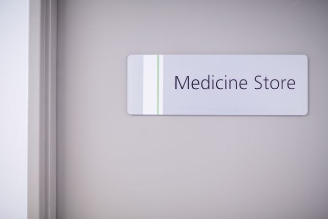 Image shows entrance of a medicine store in a hospital, featuring a sign on the door. Useful for illustrating healthcare facilities, medical supply storage, hospital interiors, and pharmacy-related content.