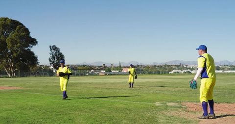 Baseball teammates walking on field in bright yellow uniforms under clear blue sky