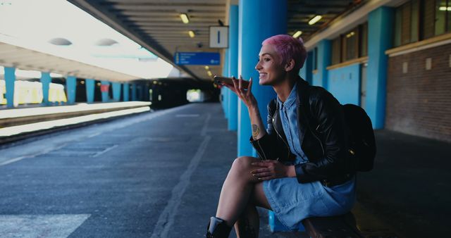 Young woman with pink hair recording voice message at train station - Download Free Stock Images Pikwizard.com