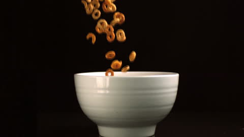 Slow Motion Pouring Loop Cereal into Bowl Against Black Background