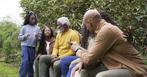 Diverse Multigenerational Family Relaxing and Chatting on Garden Wall