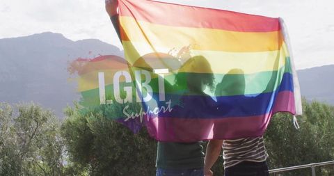 Couple holding rainbow pride flag on mountain terrace celebrating lgbt support