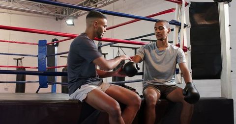 Boxing partners adjusting gloves at ring demonstrating teamwork and training focus