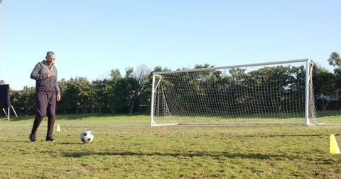 Man Practicing Soccer Kick on Rugged Grass Field
