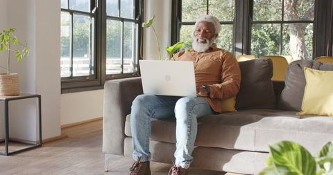Senior man enjoying technology on sofa in modern living room
