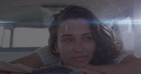 Reclining woman resting chin on blanket by window, cozy backlit morning with lens flare