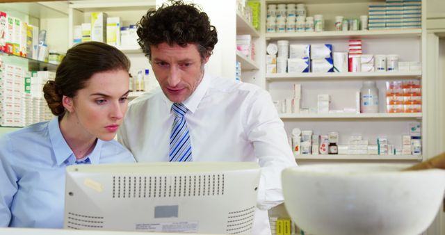 Pharmacists in pharmacy reviewing information on computer. Useful for illustrating teamwork in healthcare, medication management, and professional collaboration in retail pharmacy settings. Can be used in medical journals, pharmacy services advertisements, and educational material on pharmacy practices.