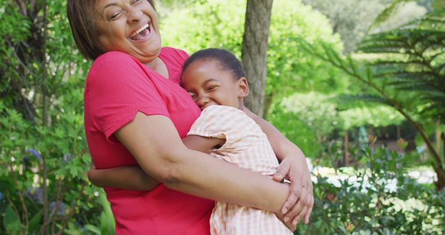 Happy african american grandmother and granddaughter hugging and having fun in garden. family, togetherness and spending quality time outdoors.