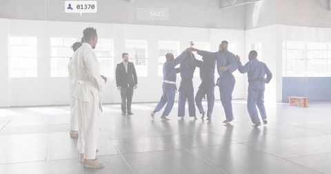 Martial arts team lifting trophy and celebrating victory in dojo training hall