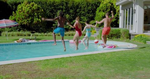 Diverse friends laughing and splashing in backyard pool party