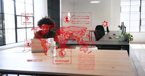 Middle-Eastern man typing on laptop with red holographic world map cybersecurity visuals